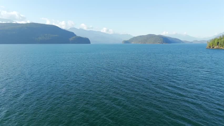 Smooth aerial flight over Harrison Lake, British Columbia, Canada, showcasing calm turquoise waters, surrounding forests, and serene natural landscapes.