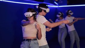 Young couple in VR glasses playing video game against another couple. Friends are enthusiastically playing a game in a virtual reality headset and using joysticks  - Powered by Shutterstock - Get 15% off with code: PIKWIZARD15