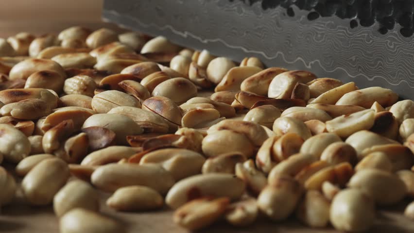 Roasted peanuts being finely chopped with a knife.