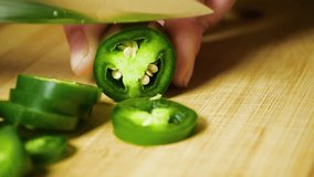 Chef Hand Cutting Green Jalapeno Pepper with Sharp Knife onto Cutting Board into Pile of Slices in Slow Motion - Powered by Shutterstock - Get 15% off with code: PIKWIZARD15