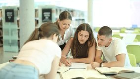 Group of students talking, reading books and taking notes at table in library  - Powered by Shutterstock - Get 15% off with code: PIKWIZARD15