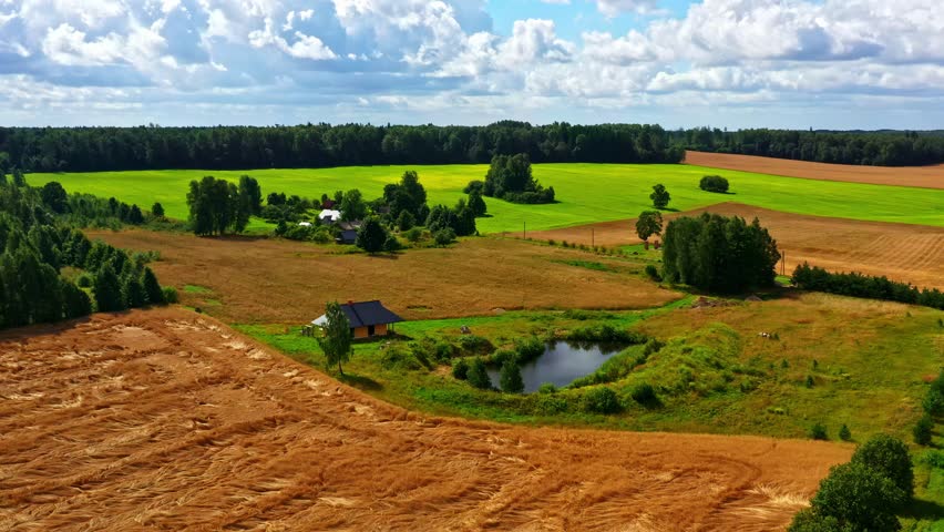 Aerial view of countryside landscape with fields, pond, and farm buildings