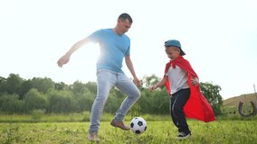 Father and son playing with soccer ball. Soccer father and son playing outdoors. A field of grass and a cape of grassy fun for bonding. A dad and his son kicking a soccer ball lifestyle around. - Powered by Shutterstock - Get 15% off with code: PIKWIZARD15