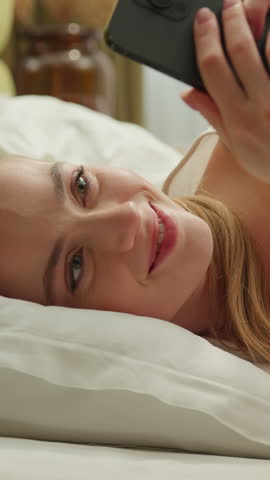 Caucasian woman morning scrolling mobile phone lying in bed application technology digital cyberspace app chatting happy carefree cheerful female girl at home social media addict influencer messaging