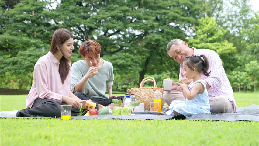 Happy multi generational Asian family enjoying picnic in the park,  Creating joyful outdoor lifestyle moment