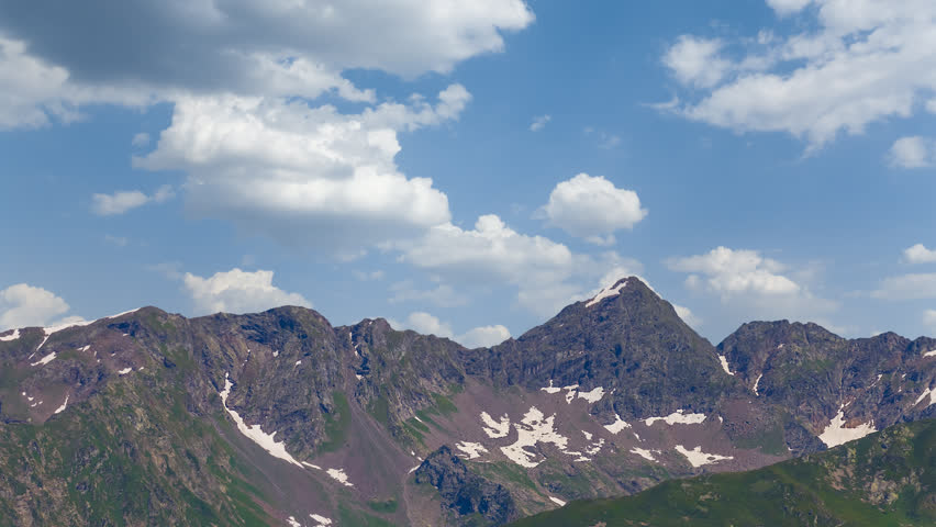 green mountain ridge under cumulus clouds time lapse scene