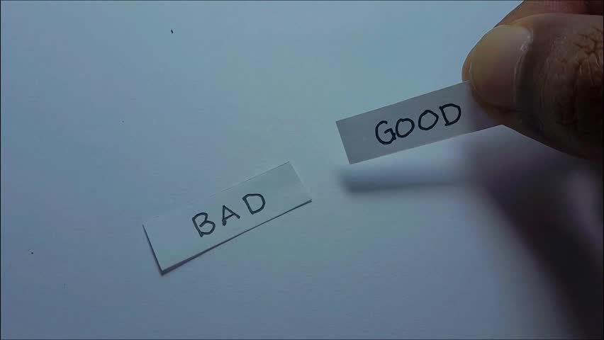 A close-up shot of a hand crossing out the word “Bad” on paper and replacing it with “Good.” Symbol of making the right choice and positivity.