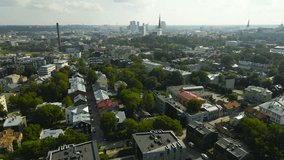 Aerial drone footage flying over kalamaja green summer neighbourhood in Tallinn Estonia during a summer day with church towers and cityscape visible in the horizon with smog. Modern apartments visible - Powered by Shutterstock - Get 15% off with code: PIKWIZARD15