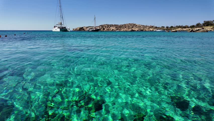 Summer vacation in Mykonos, close up view of turquoise lagoon with crystal clear water in Greece, holiday on the Greek islands, Greek paradise, idyllic tourist beach with luxury yachts 