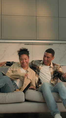 Positive African American couple falling on new couch resting comfortable hugging together smiling laughing enjoying relocation buying house man woman happy family owners enjoy tenant moving day loan