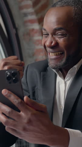 African American business man businessman winning with mobile phone web prize virtual casino bet success ethnic middle-aged adult entrepreneur executive in office male win money good offer message
