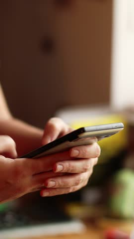 A Woman Hand Texting on a Smartphone, vertical close up view. Close-up of a Hand Typing on a Smartphone. A Woman Using a Messaging App on a Smartphone.