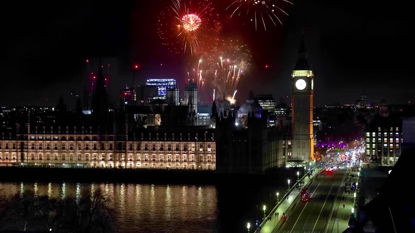 Elevated view of the Big Ben clocktower, Westminster Palace and Bridge in London, England, during night time with fireworks behind