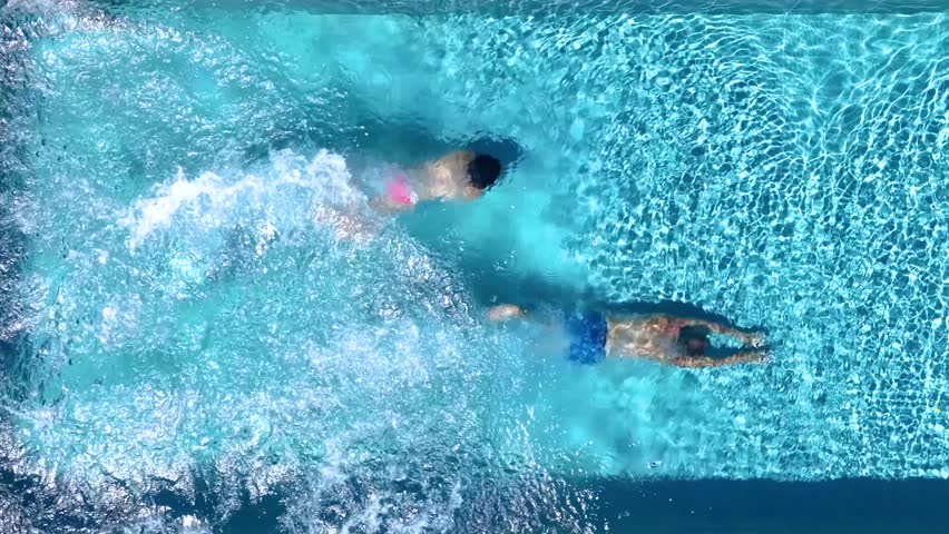 Aerial top down slow motion view of a holiday couple diving into the swimming pool, background of a summer concept