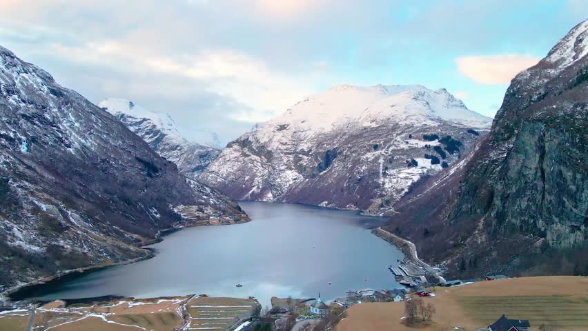 This drone footage shows the beauty of Fossevandring falls cascading into the serene Geirangerfjord, surrounded by snow capped mountains and pristine winter landscapes in Western Norway.