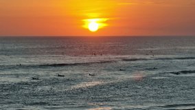 Surfers waiting for perfect wave at sunset in Bali, Indonesia, create striking silhouettes against a vibrant orange and yellow sky, essence of tropical paradise. Beautiful nature travel background - Powered by Shutterstock - Get 15% off with code: PIKWIZARD15