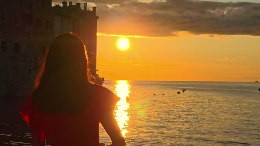Silhouette Of Woman Watching Sunset Over Sea, Golden Sun Reflecting On Water Surface, Romantic And Peaceful Moment In Rovinj Croatia Old Town