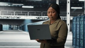 Technician in server room using laptop to upgrade rigs for increase in clients workload capacity. African american woman in data center configures equipment, improving processing speed, camera B - Powered by Shutterstock - Get 15% off with code: PIKWIZARD15