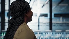 Technician in data center overseeing large scale IT gear to maintain seamless operations. IT professional walking in server hub, doing network management for increased uptime, camera B - Powered by Shutterstock - Get 15% off with code: PIKWIZARD15