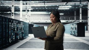 Technician in server room using laptop to upgrade rigs for increase in clients workload capacity. African american woman in data center configures equipment, improving processing speed, camera A - Powered by Shutterstock - Get 15% off with code: PIKWIZARD15