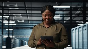 Data center software developer monitors data center metrics on tablet to enhance operational effectiveness. Woman in server room using app device analytics to predict performance, camera B - Powered by Shutterstock - Get 15% off with code: PIKWIZARD15