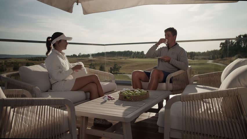 Successful young couple rests drinking coffee after golf training