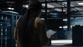 Engineer in data center using tablet to deploy secure server architecture. African american woman in server hub using device to do rollout of cybersecurity framework, camera B - Powered by Shutterstock - Get 15% off with code: PIKWIZARD15