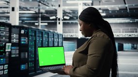 Server room admin uses green screen laptop to upgrade mainframes for increase in workload capacity. Data center worker configures gear with mockup notebook, improving processing speed, camera A - Powered by Shutterstock - Get 15% off with code: PIKWIZARD15