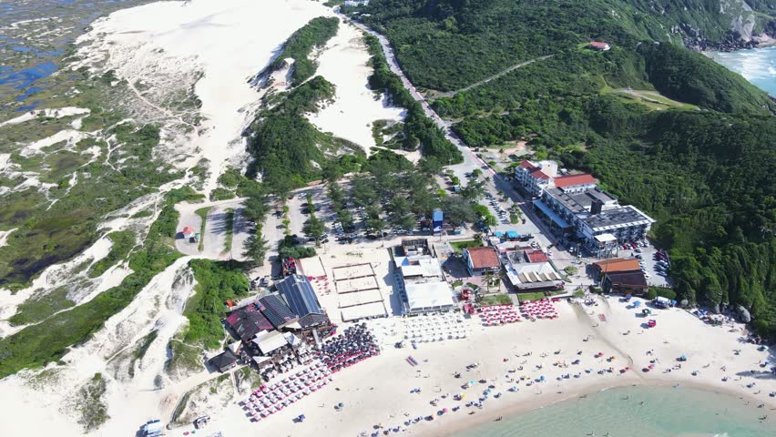 Aerial view of Joaquina Beach in Florianopolis, Santa Catarina, and the Joaquina Dunes near Lagoa da Conceição on a beautiful sunny day with the beach crowded with people