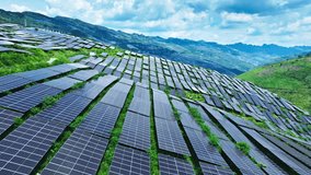 Aerial shot of a large solar farm with photovoltaic panels covering the green mountain slopes, generating clean and renewable electricity. - Powered by Shutterstock - Get 15% off with code: PIKWIZARD15