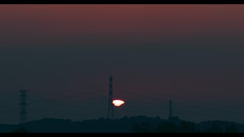 The morning sun rising beyond towers.

