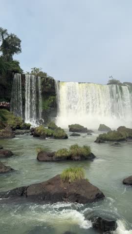 Iguazu Falls waterfall river scene with mist and rocks in the water, South America.