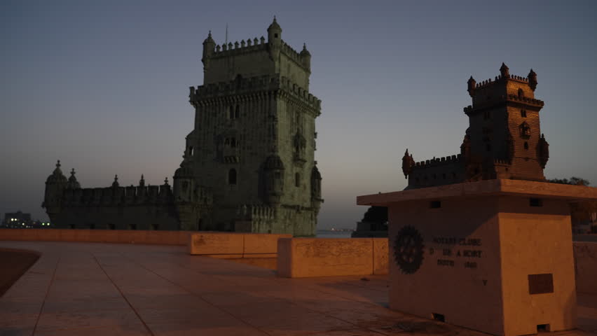 View at the illuminated Belem tower at night along the bank of Tagus River in Lisbon, Portugal, during blue hour at dusk.