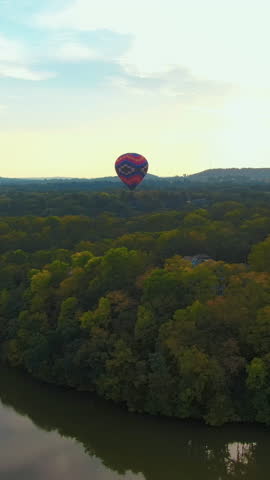 Vertical Aerial Tracking Shot of a Hot Air Balloon Over a Luxury Lakeside Community at Golden Hour