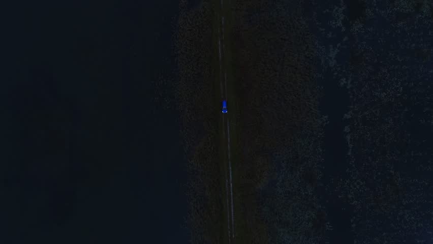 Aerial cinematic view of car on wetland road captured from great altitude