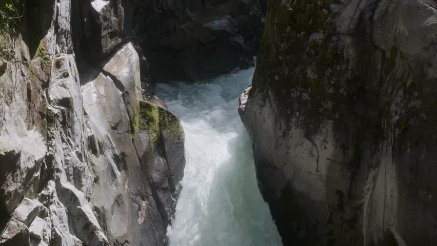 Powerful glacier water rushing through narrow rock walls near the Stubai Glacier in Tyrol, Austria. Camera tilting downwards.