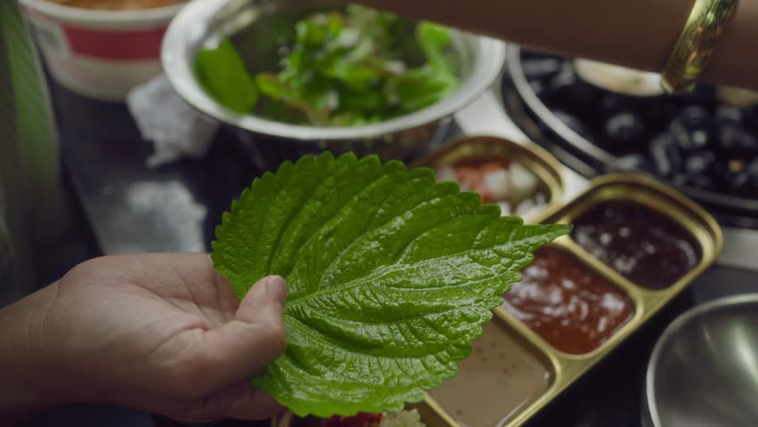 Hand cooking smoked grilled pork on iron grill pan in Korean BBQ in restaurant. Traditional Korea style food barbecue pork belly steak on charcoal grill.