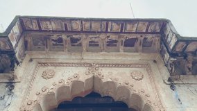 Camera tilts down from the detailed carvings of an old fort entrance to reveal a long arched passage leading outside, showing historic architecture - Powered by Shutterstock - Get 15% off with code: PIKWIZARD15