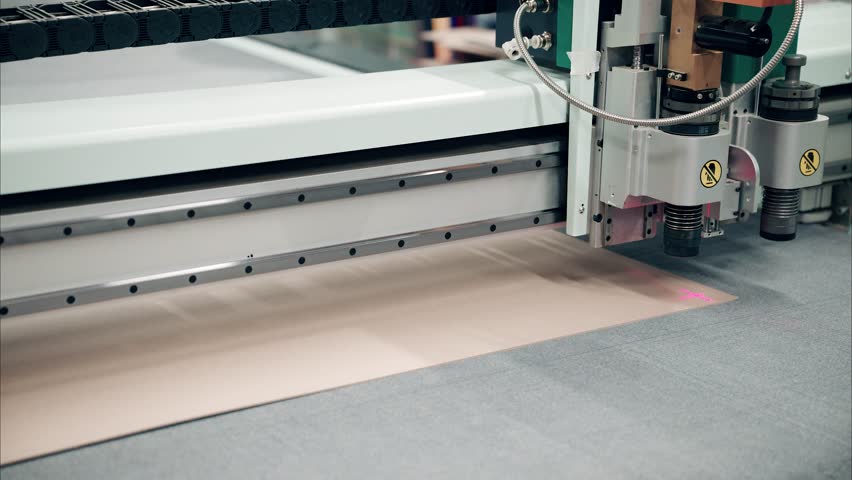 Crafting precision with an industrial plotter cutting through cardboard in a dynamic workspace setting