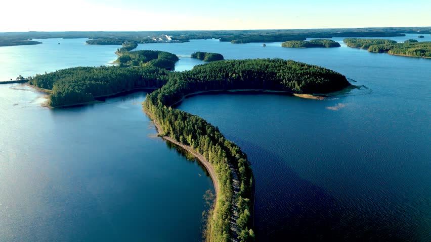 Majestic views of the unique esker landscape in Punkaharju, Finland, where lush forests meet the serene waters. A natural road between green pine trees and a lake at Punkaharju Nature Reserve 