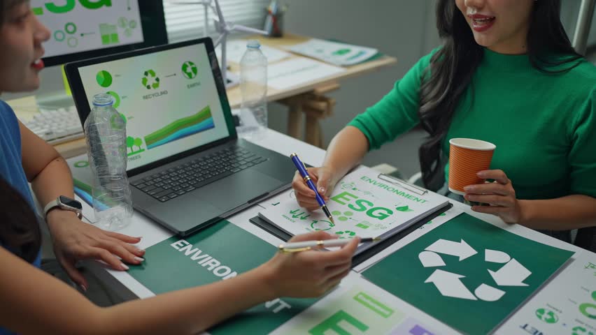 Businesswomen discussing environmental, social, and governance - esg - with recycle logo and environment data graph