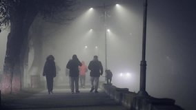 Group of unrecognizable people walking down a street in the fog. The street is empty and the car is parked on the side of the road - Powered by Shutterstock - Get 15% off with code: PIKWIZARD15