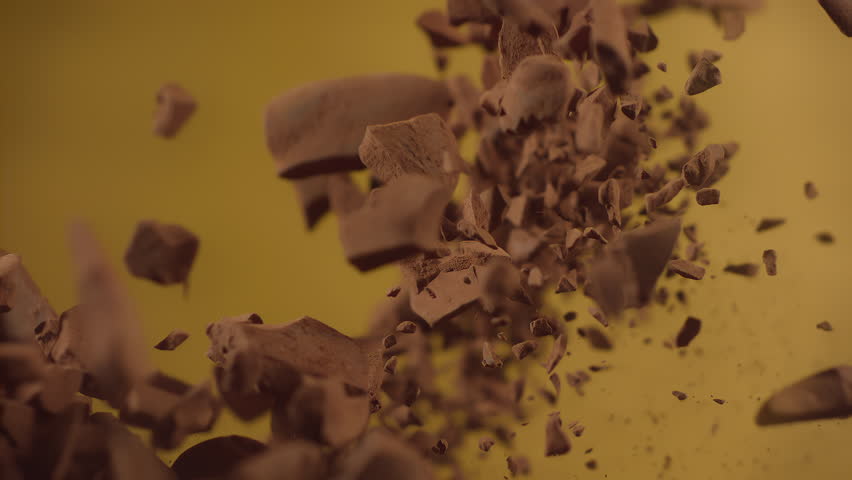 Raw chocolate chunks with powdered chocolate flying in super slow motion. Pieces of chocolate with cocoa powder drops explosion. High speed 1000fps