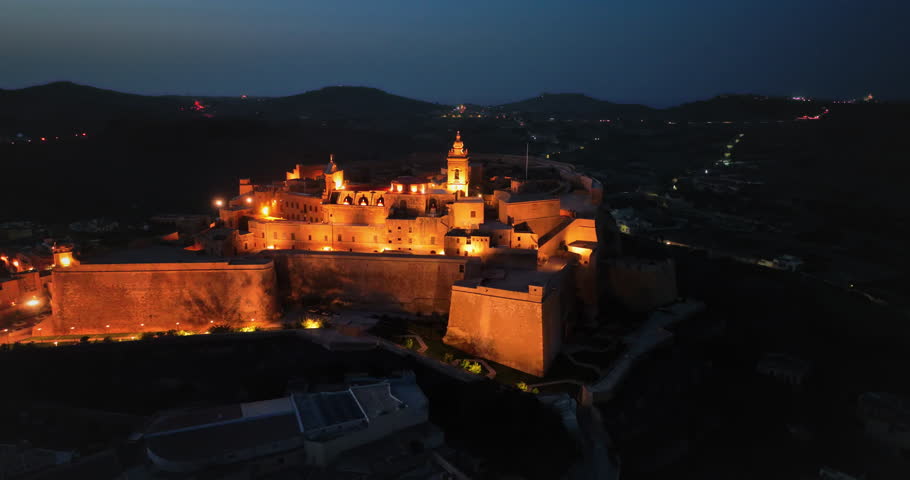 Malta, Comino island: illuminated Cittadella in Gozo, Malta, ancient fortress tourist historical architecture highlighting its majestic panorama at night. Aerial view drone flight footage