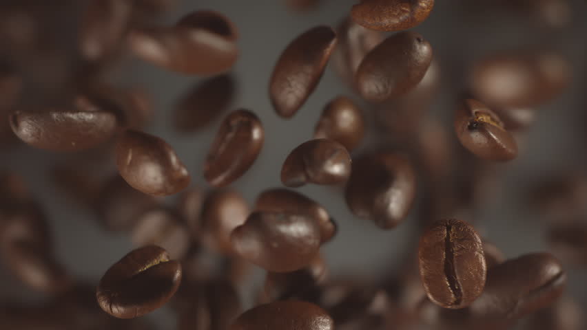Super slow motion shot of falling roasted coffee beans with smoke in macro. Roasting flying coffee. Whole coffee explosion close up vertical video