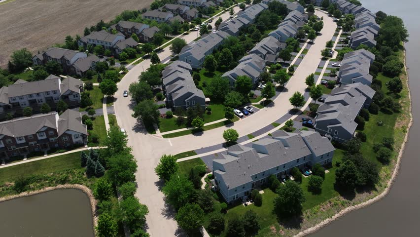 Aerial approach to curved suburban streets with evenly spaced houses and green lawns, idyllic perfect backdrop for town