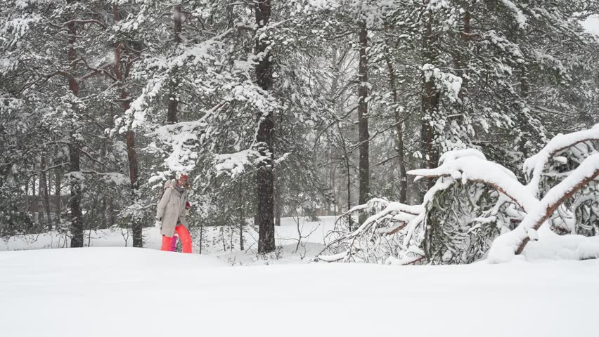 Middle-aged mother and teenage daughter enjoying walk in snowy Finland forest. Warm clothing, family values, lifestyle, togetherness and joyful winter holiday season atmosphere.