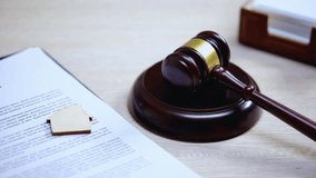 Close-up of a wooden house sign on a legal document with a judge’s gavel striking on a sound block, symbolizing property law, real estate, ownership, contracts, and legal judgment in justice systems. - Powered by Shutterstock - Get 15% off with code: PIKWIZARD15