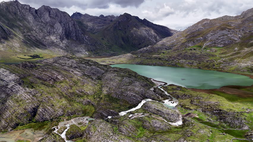 Scenic Andes mountain lake in Peru with turquoise water, rugged cliffs, and dramatic peaks under cloudy sky, pristine nature and breathtaking highland landscape