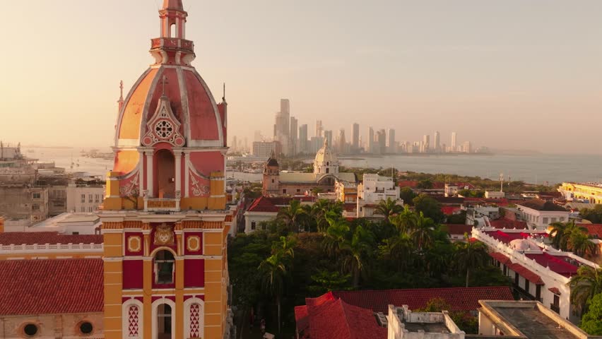 Drone shot of a church tower in Cartagena’s historic center at sunrise, featuring Santuario de San Pedro Claver with modern skyline in the background